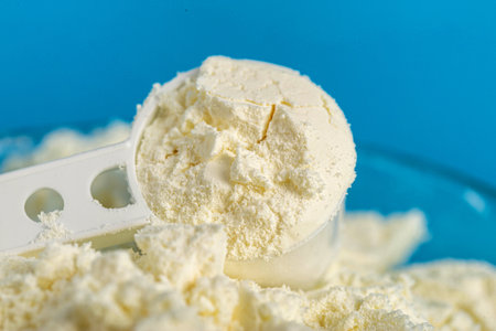 Measuring spoon in a plate with dry baby food for preparing infant formula. Enriched with...