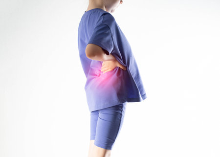 A girl in a purple suit holds her hand on a kidney in her back on a white background. Concept of...