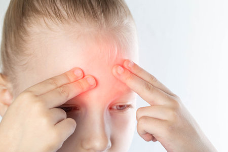 The girl holds her forehead with her hands, pain in her head. The concept of sinusitis in children. Inflammation of the maxillary sinuses. Treatment of sinusitis and nasal congestion.の写真素材