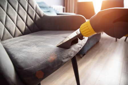 Services for washing and cleaning upholstered furniture with a vacuum cleaner. Cleaning dirty gray chairs in the apartment.の写真素材