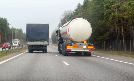 A truck with a semi-trailer tanker transports dangerous cargo along the highway - liquefied gas. Logistics of dangerous goodsの写真素材