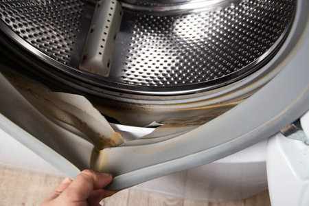 A washing machine repairman changes the rubber seal of the washing machine hatchの写真素材