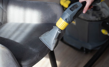 Dry cleaning gray soft chairs made of fabric upholstery with a washing vacuum cleaner. Cleaning company services.の写真素材
