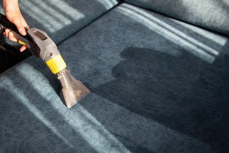 Cleaning the sofa from dirt with a washing vacuum cleaner. Cleaning company services, business