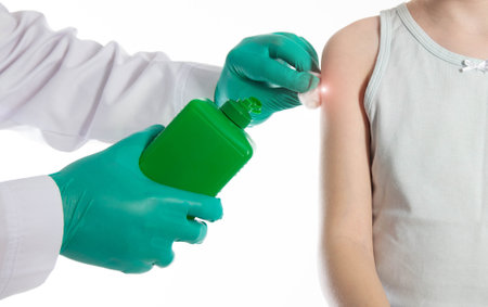 Doctor's hands with cotton wool and antiseptic treating the skin before vaccination against tetanus and viral hepatitis. Revaccination of children.の写真素材