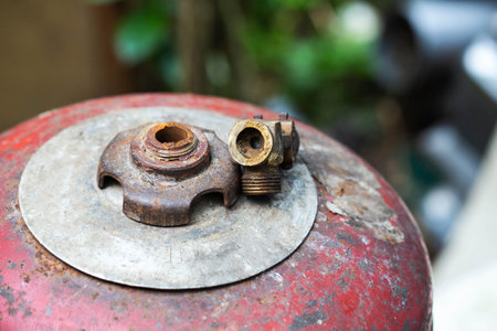 A broken gas cylinder valve lies on a red cylinder. Danger of gas leakage and explosion. Copy space for textの写真素材