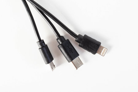 Universal black 3 in 1 charging cable with different charging connectors on a white background, close-up. Type-c, usb-c, micro-usb, chargingの写真素材
