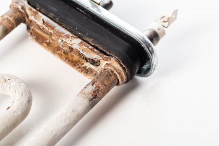 Old electric heating element from a washing machine on a white background. Scale and rust due to hard water.の写真素材