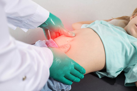 The doctor's hands in green gloves probe the stomach of a little girl who has bloating and pain in the intestines. Impaired digestion of food, dysbacteriosis.の写真素材