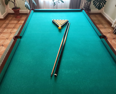 Balls with a cue lie on the green cloth of a billiard table, background.の写真素材