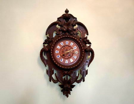 Old antique wall clock on a white wall, museum exhibit