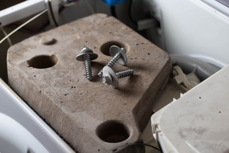 Bolts and tools lie on the counterweight of the washing machine. Concept of noise, vibration and rumble due to an unscrewed counterweight.の写真素材