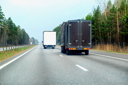 A new brown truck van with a semi-trailer transports cargo along a country road in the spring. Copy space for textの写真素材