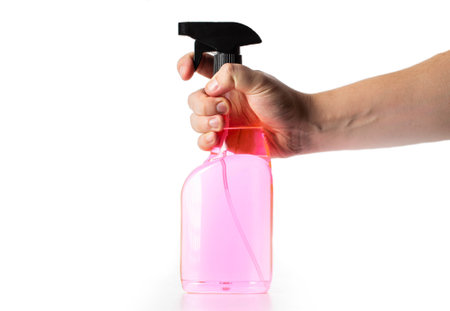 A bottle with a spray and pink liquid in a man's hand on a white background, isolate. Anti-ice, ice and lock defroster, cleaningの写真素材