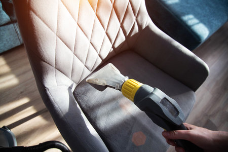 Services for washing and cleaning upholstered furniture with a vacuum cleaner. Cleaning dirty gray chairs in the apartment.の写真素材