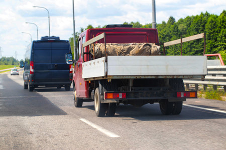 An open flatbed truck drives on a highway in summer. Transportation of goods up to 5 tons. Rental of trucks for regional and international transportation, industryの写真素材