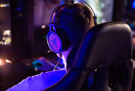 Professional gamer is playing a computer game on PC at cyber club. Player is participating in E-sports competition at gaming cafe. Gamer playing tactical shooter game during cyber sport tournamentの写真素材
