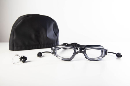 Transparent swimming goggles with earplugs and nose clip and cap on white background, close-upの写真素材