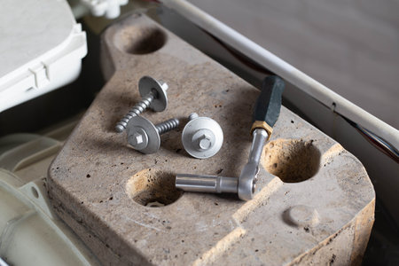 Bolts and tools lie on the counterweight of the washing machine. Concept of noise, vibration and rumble due to an unscrewed counterweight.の写真素材