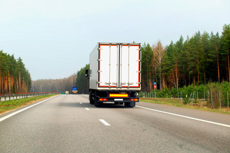A new truck with a white isothermal semi-trailer transports a load of medicines that require temperature control. A truck carries cargo in the spring against the backdrop of a forest.の写真素材