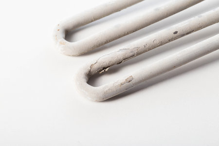 Old electric heating element from a washing machine on a white background. Scale and rust due to hard water.の写真素材
