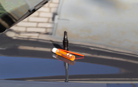 A can of black paint, rust converter and a brush on the hood of a car. Concept for removing chips from paintwork on a car, close-upの写真素材