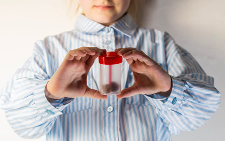 A child holds a container with a stool test in his hands. Concept of a study of stool analysis in childrenの写真素材