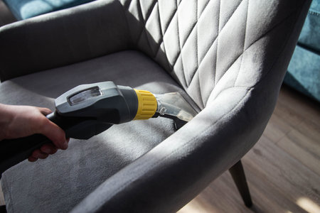 Services for washing and cleaning upholstered furniture with a vacuum cleaner. Cleaning dirty gray chairs in the apartment.の写真素材