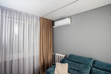 Window in a hall room with brown curtains and an air conditioner on the wall. Modern renovationの写真素材
