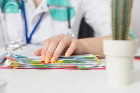 The hand of a doctor girl is on a folder with medical tests of patients. Concept of registering patients, close-up. Copy space for textの写真素材