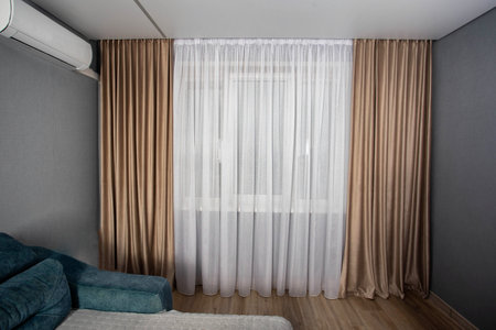 Window in a hall room with brown curtains. Modern renovationの写真素材