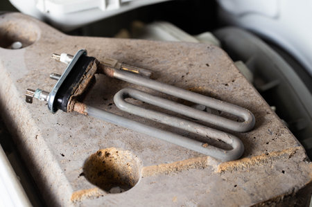 Removed electric heating element of a washing machine with scale and deposits, replacement of the heating element, industryの写真素材