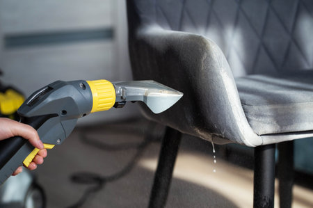Spraying a chemical from a washing vacuum cleaner when cleaning the fabric upholstery of a chair. Cleaning servicesの写真素材