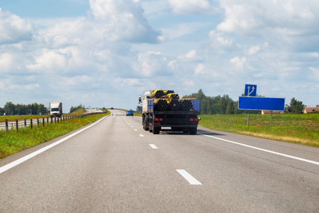 Transporting metal pipes on a semi-trailer truck along a highway in summer, industry. Transportation of metal products. Copy space for text, businessの写真素材