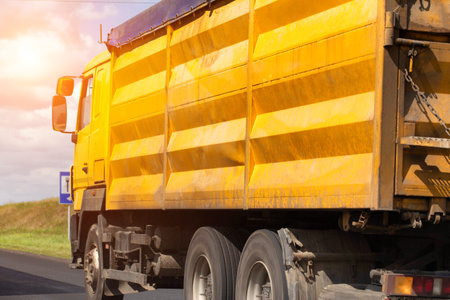 A yellow dump truck transports grain from the fields with a closed awning. Import and export of grain, transportation of agricultural productsの写真素材