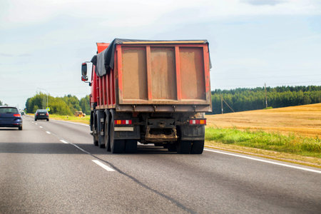 Red dump truck transports bulk cargo grain along the highway in summer. Copy space for textの写真素材