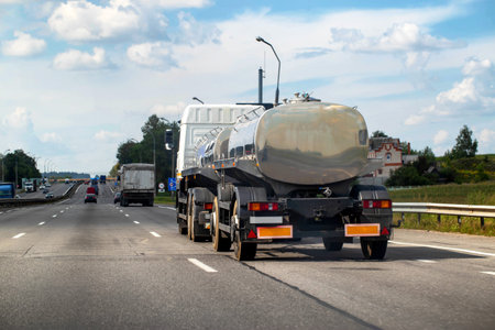A tanker truck with a tank semi-trailer transports milk and food liquids. Truck on the highway in summer. Copy space for textの写真素材