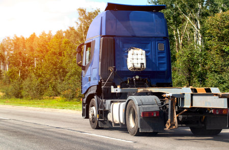 A blue cargo truck tractor rides on a highway with a semi-trailer, against the backdrop of a forest. Copy space for text, cargo transportationの写真素材