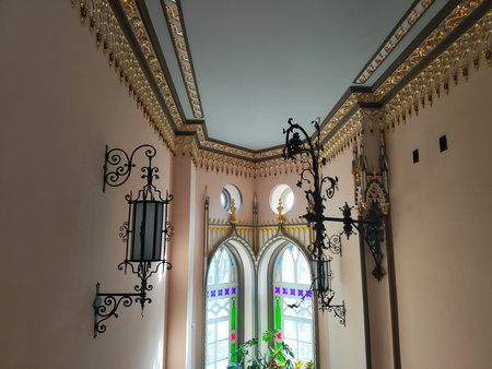 Forged wall lamps in an antique room with patterns on the ceiling and multi-colored windows, interiorの写真素材