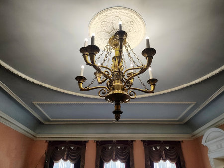 Antique chandeliers in a museum with a ceiling and walls in patterns against the background of a window.の写真素材