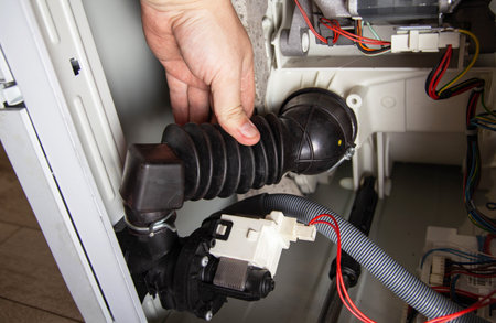 The rubber drain pipe and drain pump are clogged with clothes in the washing machine. Cleaning the water drain holeの写真素材