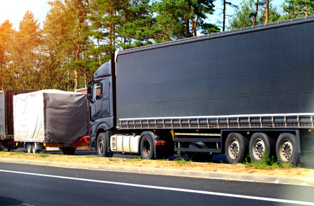 A black semi-trailer truck crashed into the trailer of another vehicle on the road. Concept of...