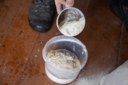 Dolomite flour in a mug against a bucket, deoxidizing the soil in the garden. Increasing crop yields