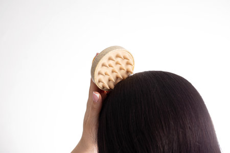 Girl holding hair and scalp massager in hand against black hair background. Copy space for text, follicles. Hair careの写真素材