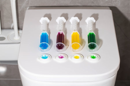 A set of multi-colored syringes with different scents on the toilet bowl in the toilet for cleaning...