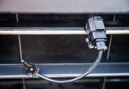 Black car outside air temperature sensor against the background of a car bumper grille. Measuring...