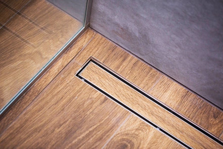 Water drain in brown wood effect tile on floor in shower without trap. Copy space for text, industryの写真素材