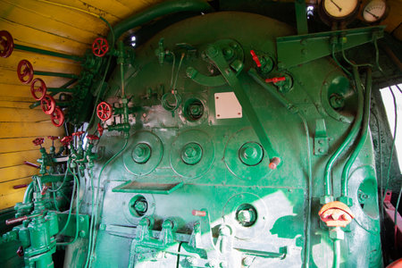 Inside a historical steam engine, the vibrant green control panel displays an array of valves and...
