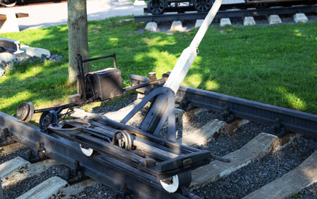 A railway switch mechanism is positioned beside the tracks at a historical train site, basking in...
