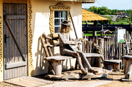 A museum exhibits depicts a village man playing the balalaika while sitting on a bench in a village with a village hut in the background.の写真素材